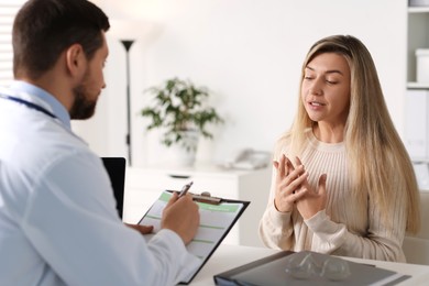 Photo of Professional doctor working with patient at white table in hospital