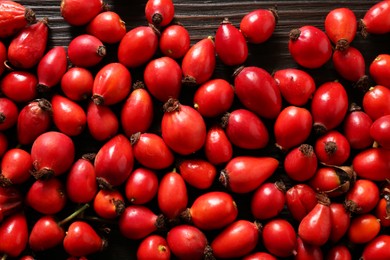 Photo of Fresh ripe rosehip berries on wooden table, flat lay