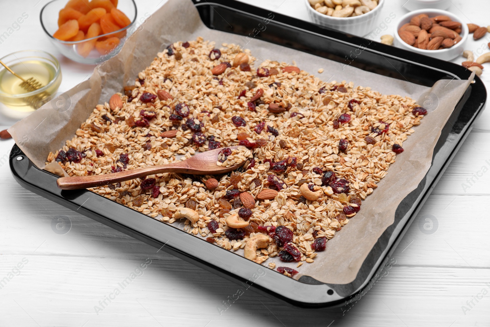 Photo of Tray with tasty granola, nuts and dry fruits on white wooden table