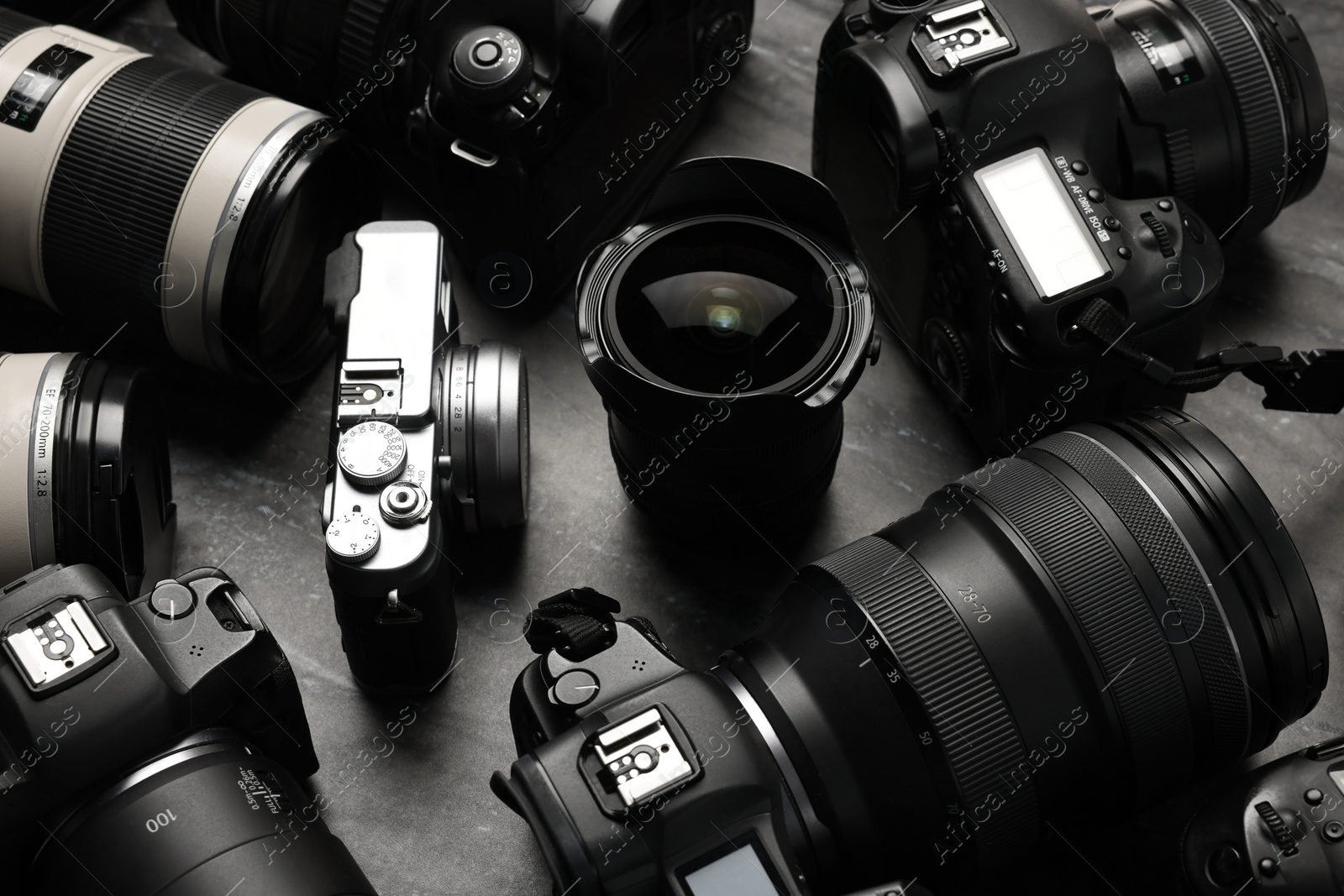 Photo of Modern cameras on dark gray table, closeup