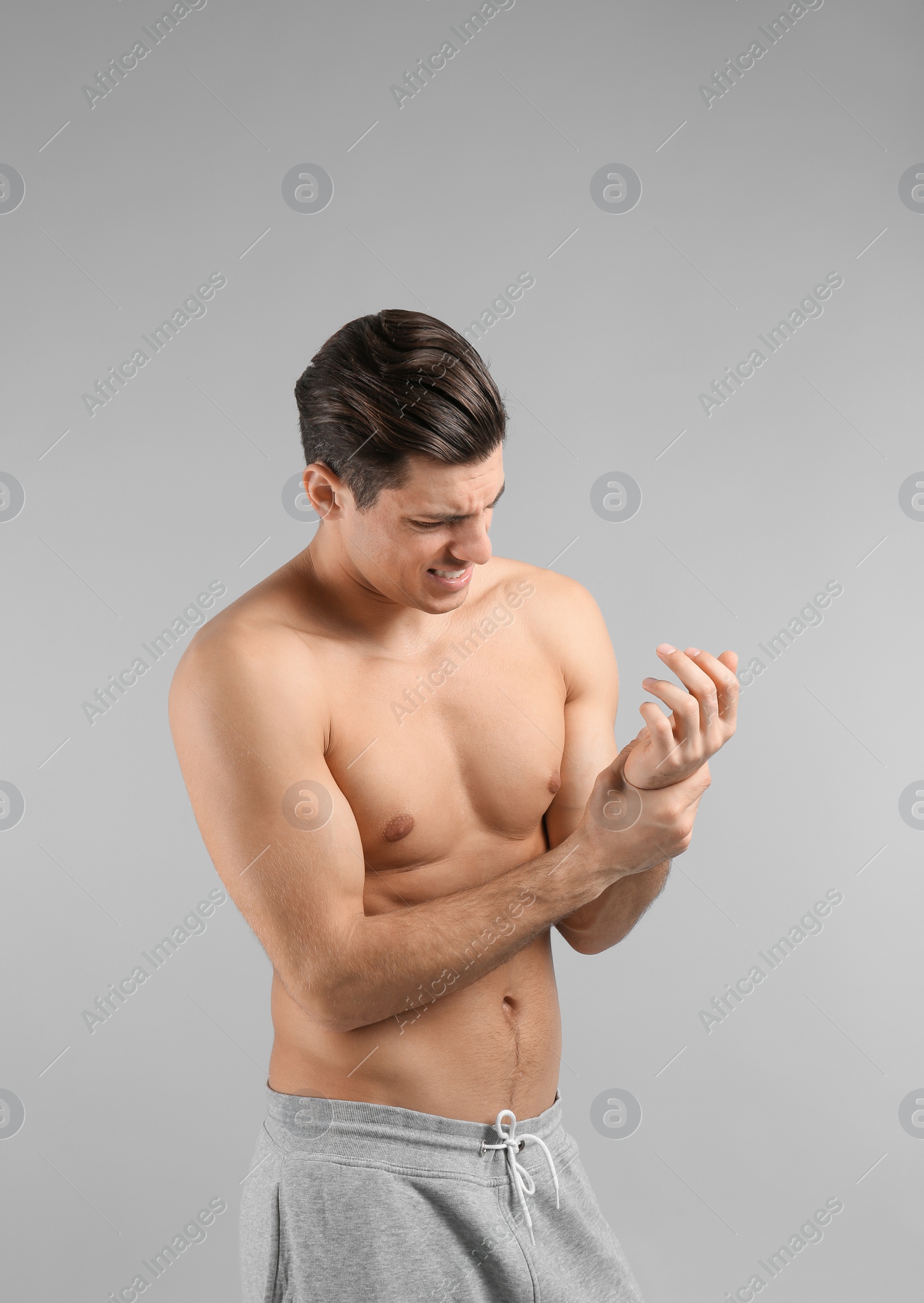 Photo of Young man suffering from pain in wrist on grey background