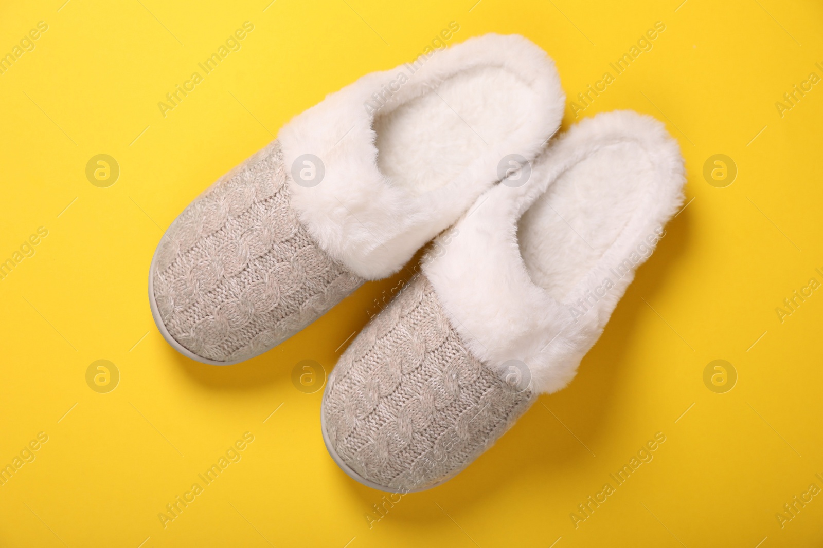 Photo of Pair of beautiful soft slippers on yellow background, top view