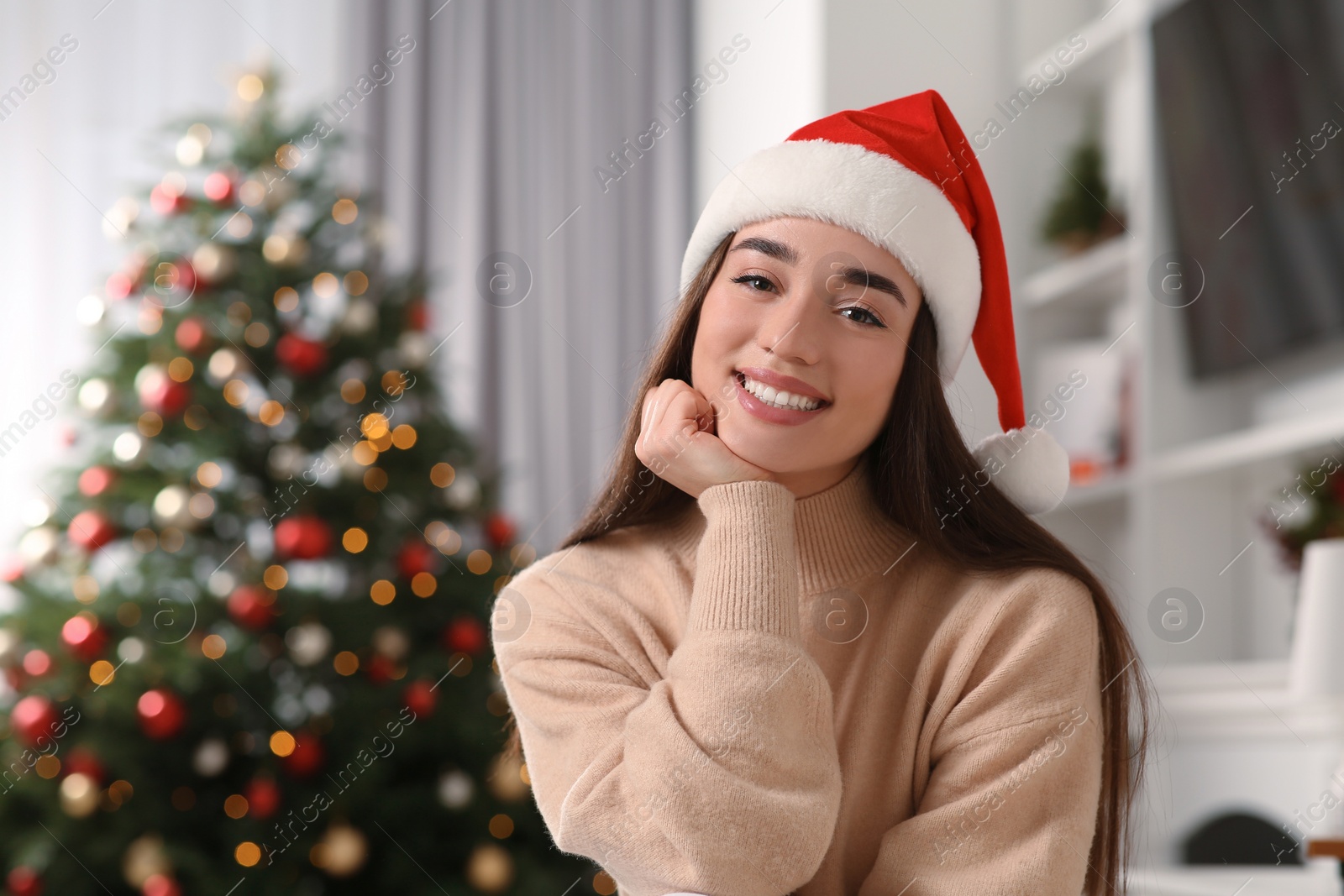 Photo of Portrait of smiling woman wearing red Christmas hat indoors. Space for text