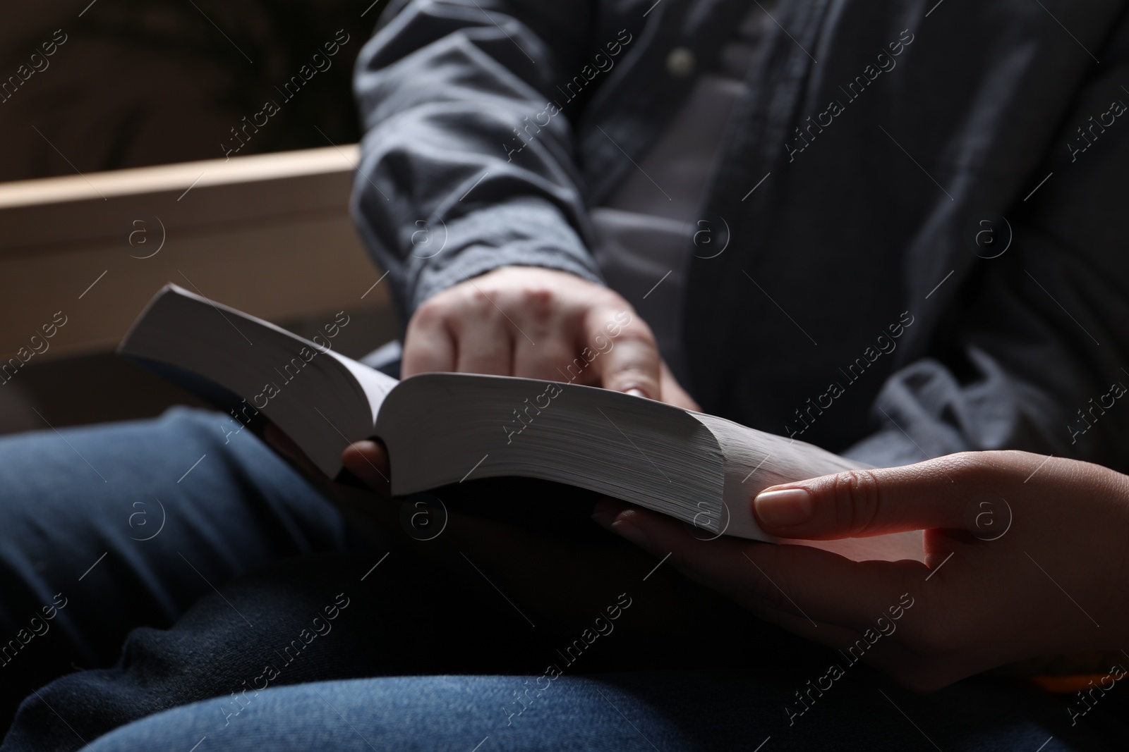 Photo of Couple sitting and reading holy Bible indoors, closeup