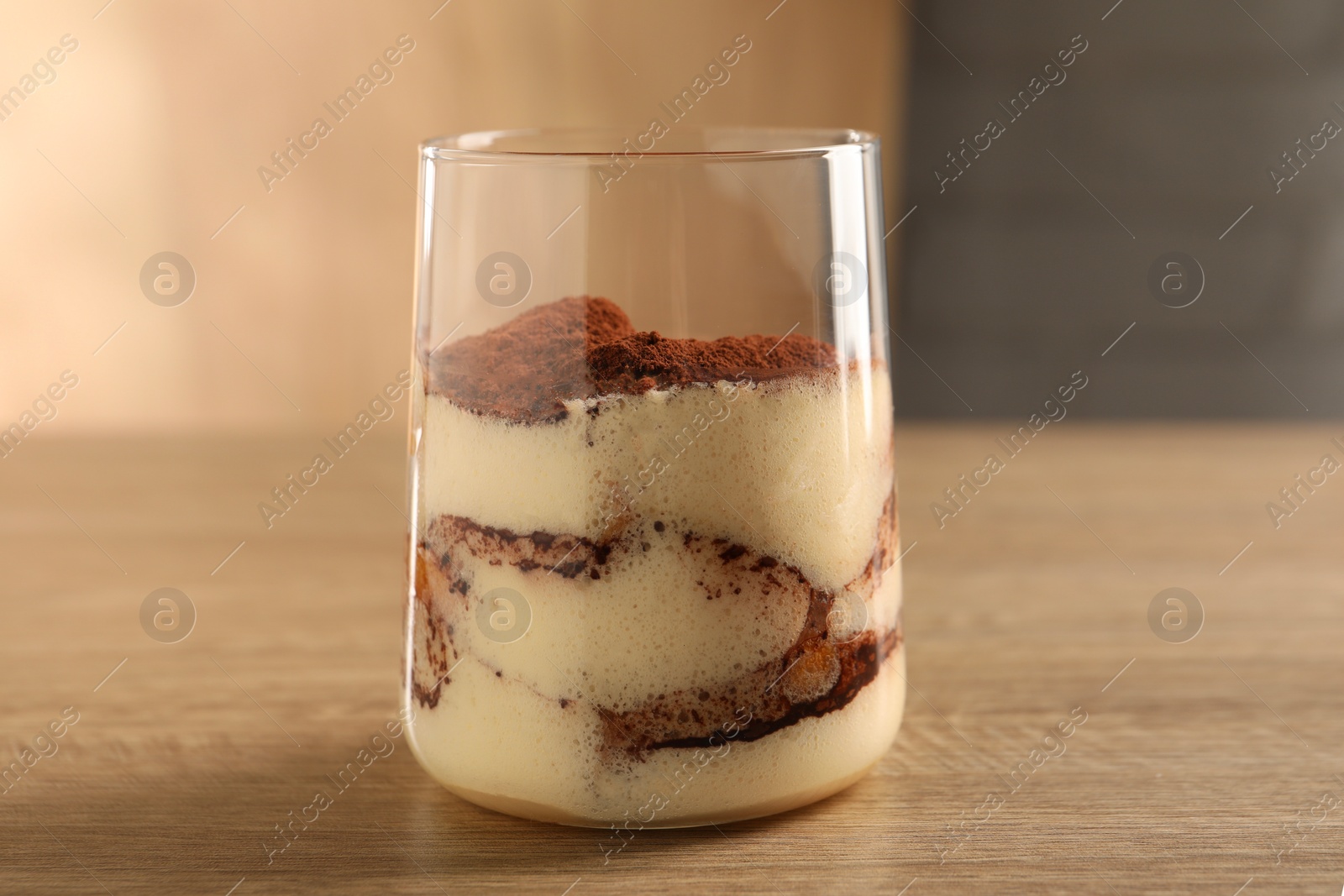 Photo of Delicious tiramisu in glass on wooden table, closeup