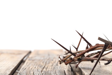 Photo of Crown of thorns on wooden table against white background, closeup with space for text. Easter attribute