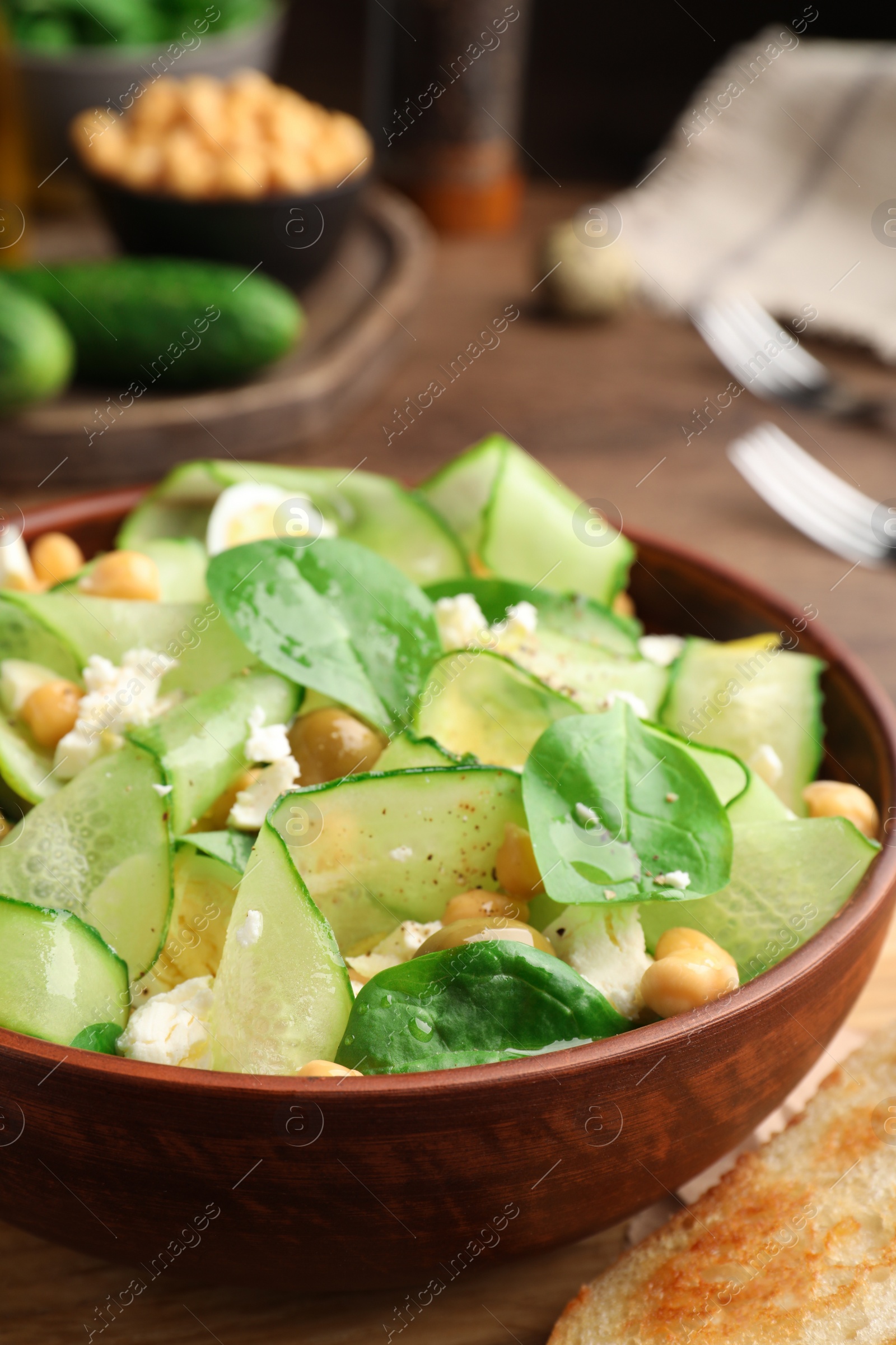 Photo of Bowl of delicious cucumber salad on wooden table, closeup