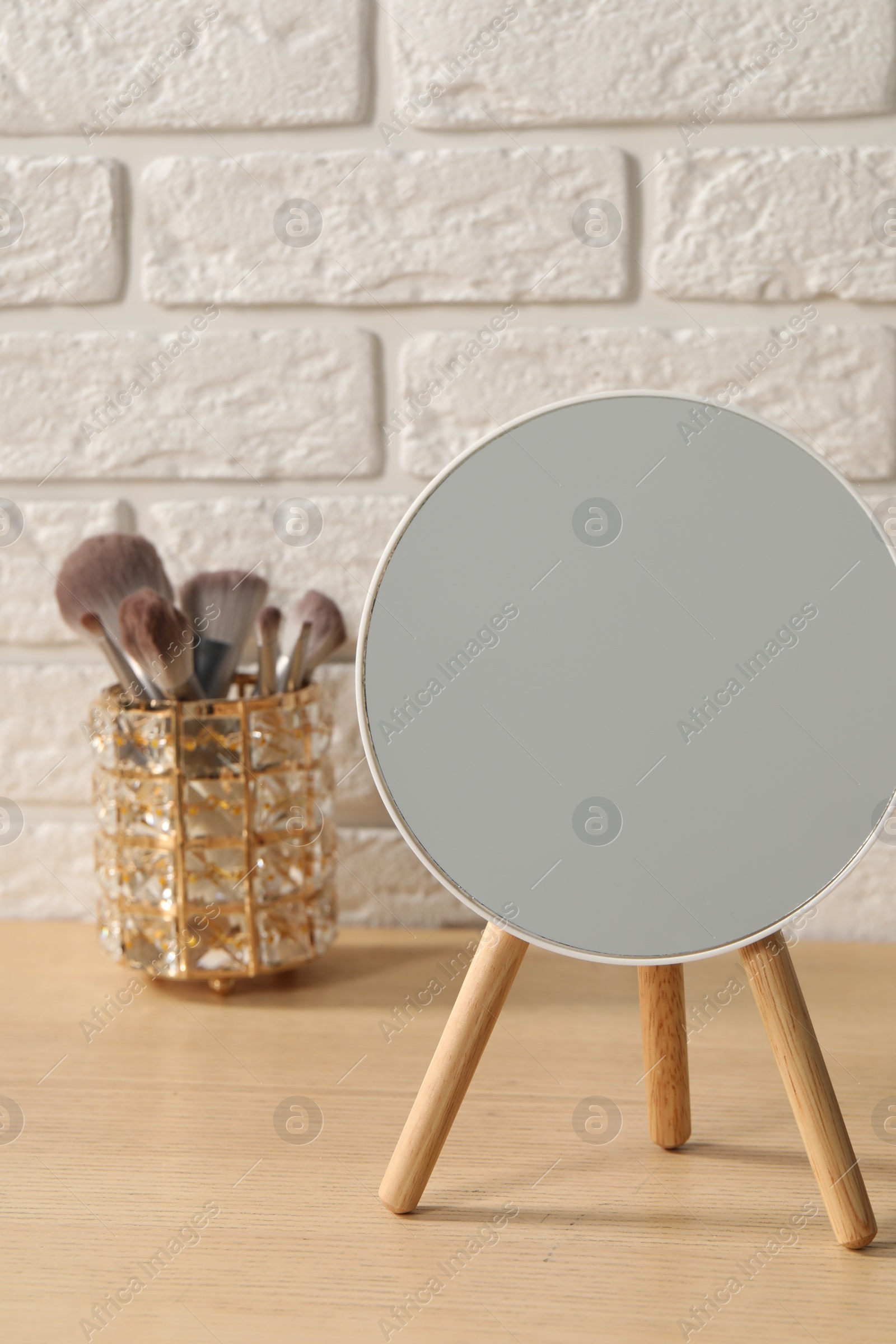 Photo of Mirror and makeup brushes on wooden dressing table in room