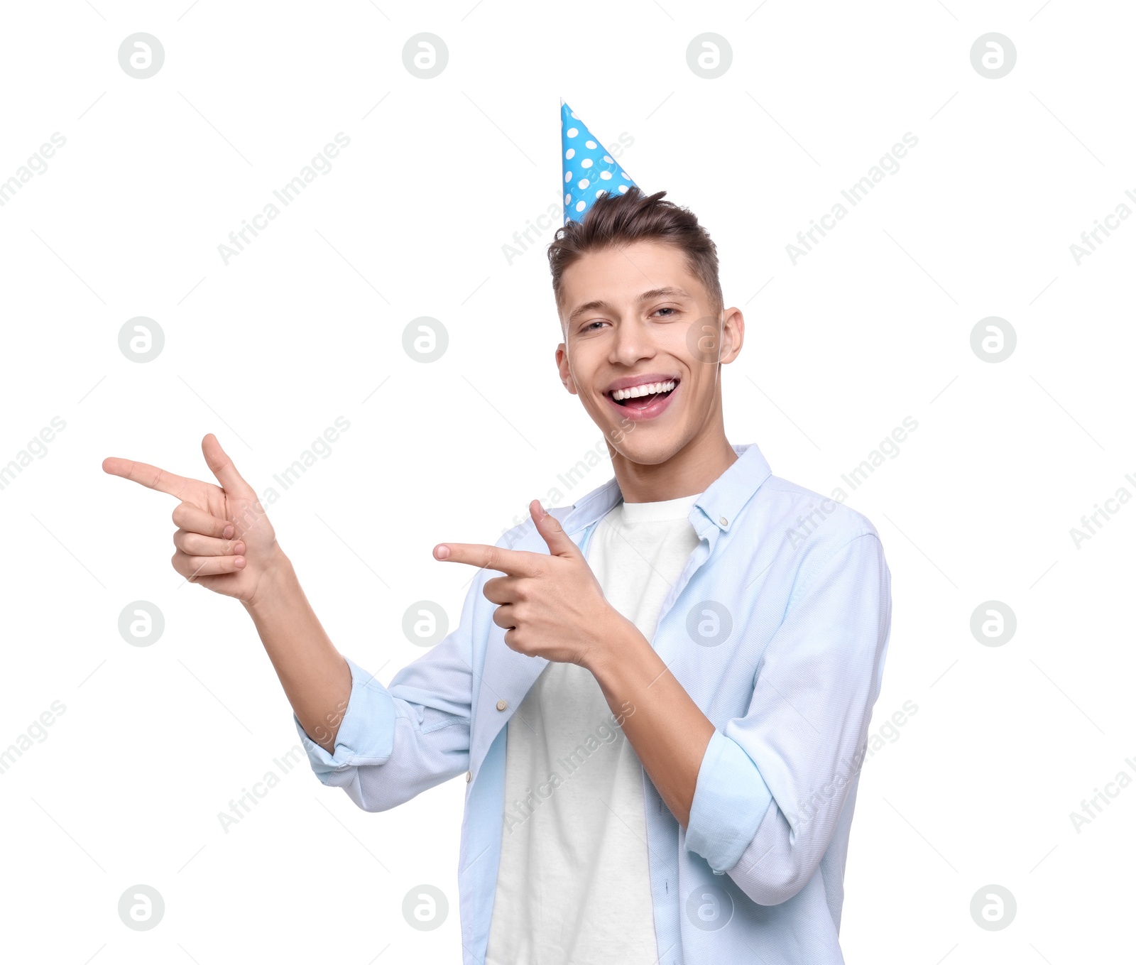 Photo of Happy young man in party hat pointing at something on white background