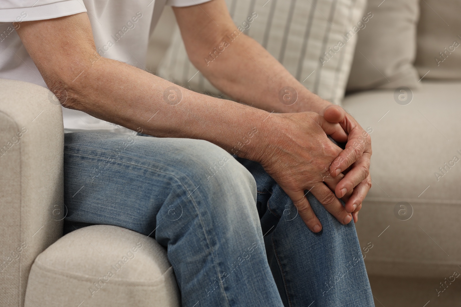 Photo of Senior man suffering from knee pain on sofa, closeup. Rheumatism symptom