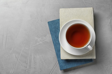Hardcover books and cup of tea on grey stone background, top view. Space for text