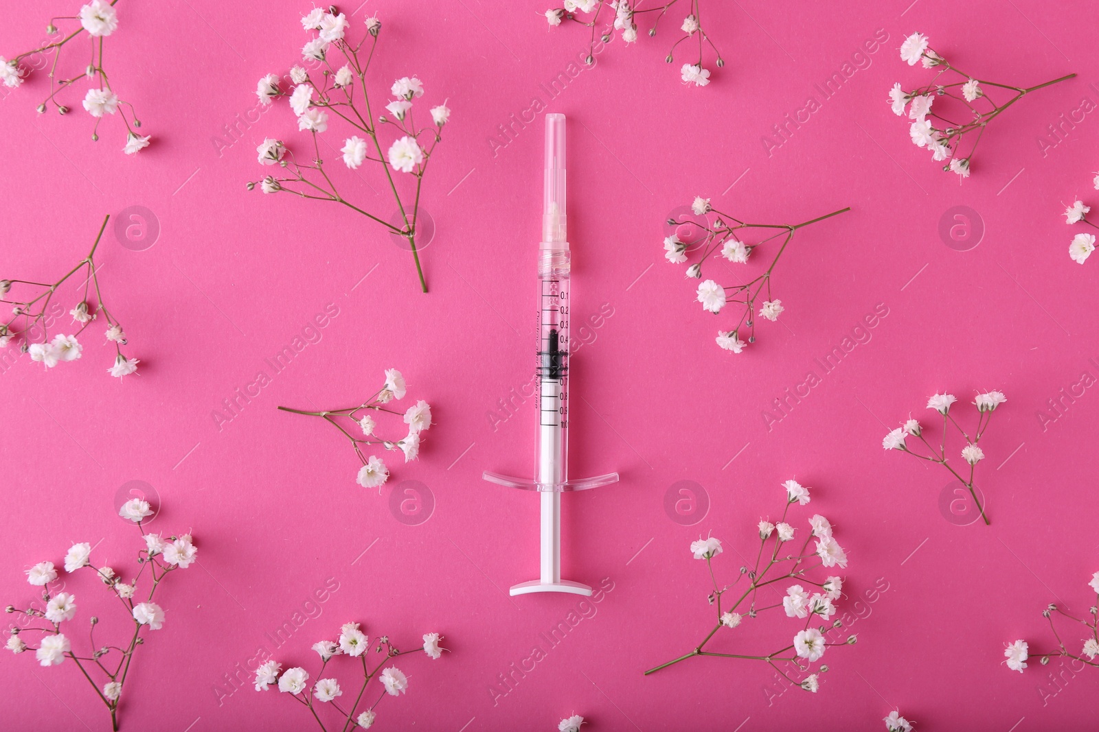 Photo of Cosmetology. Medical syringe and gypsophila flowers on pink background, flat lay