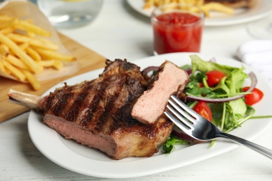 Image of Grilled steak with fresh salad on white table, closeup