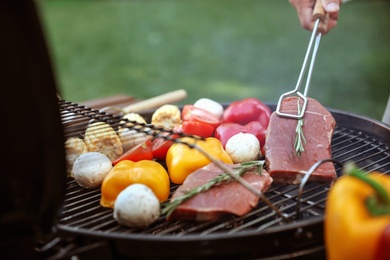 Man cooking food on barbecue grill outdoors, closeup