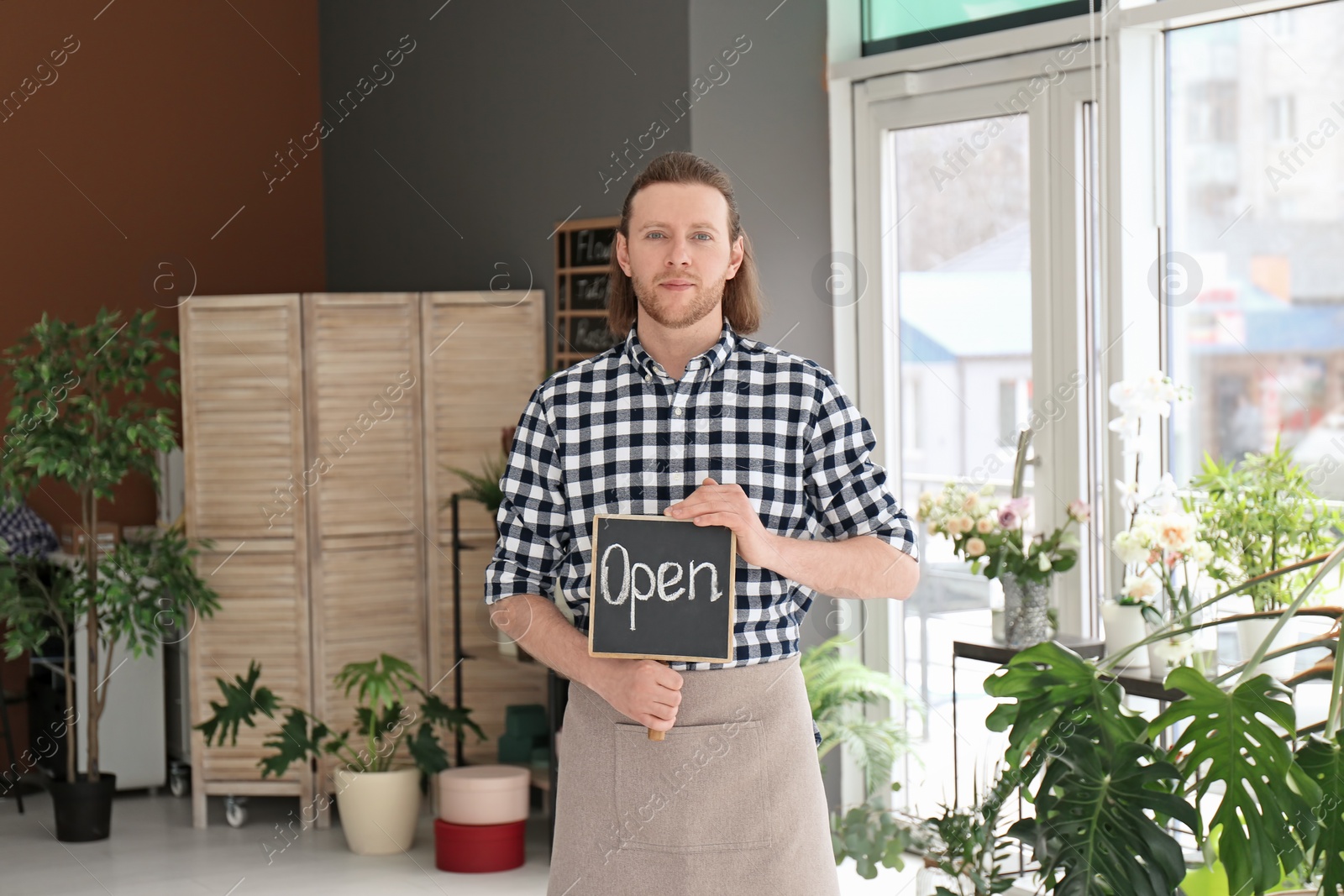 Photo of Male florist holding OPEN sign at workplace