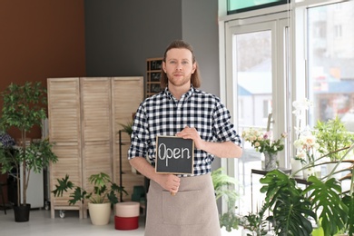 Male florist holding OPEN sign at workplace