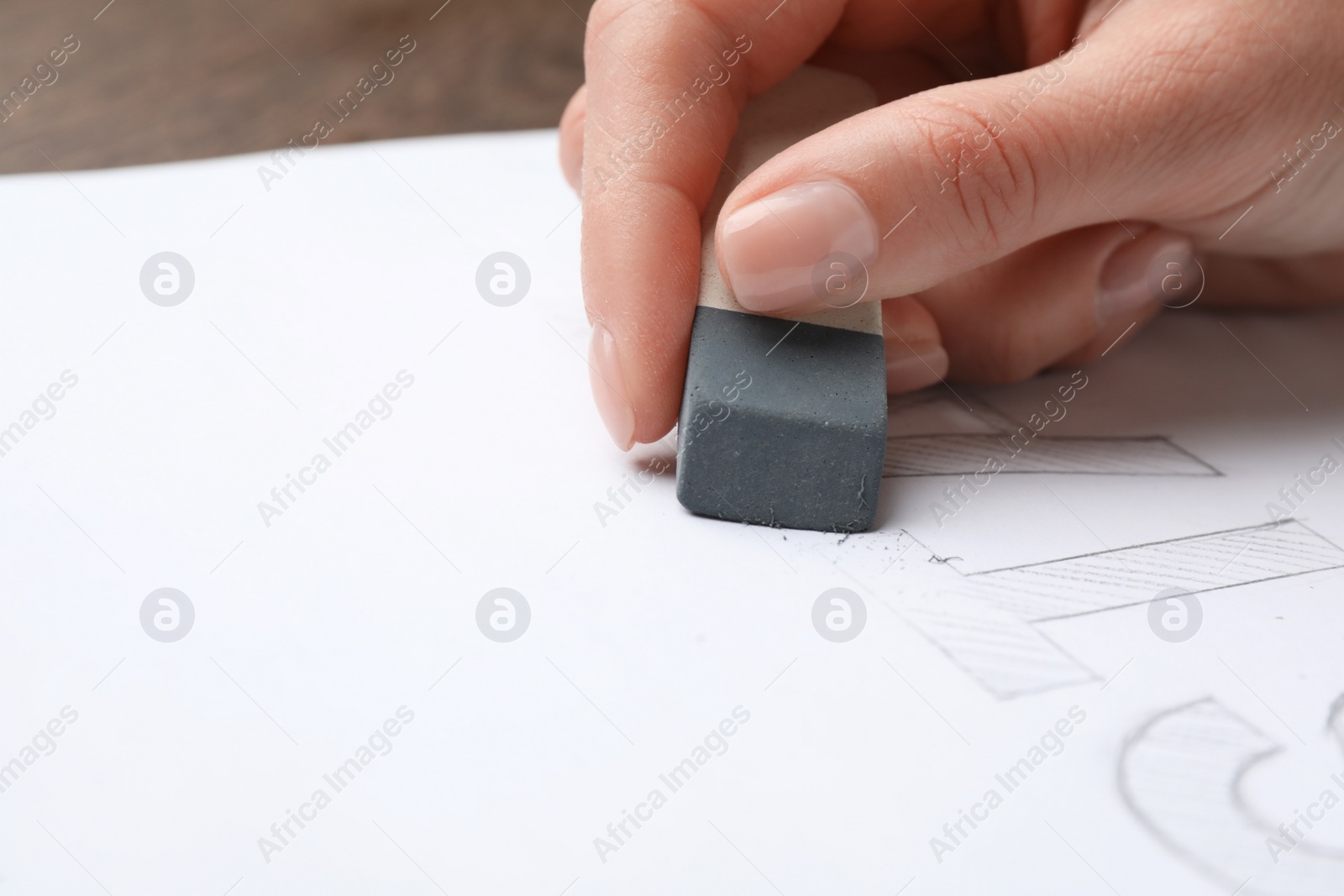 Photo of Woman erasing word on sheet of white paper at table, closeup