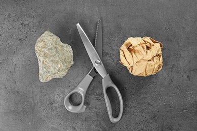 Flat lay composition with rock, paper and scissors on grey stone background