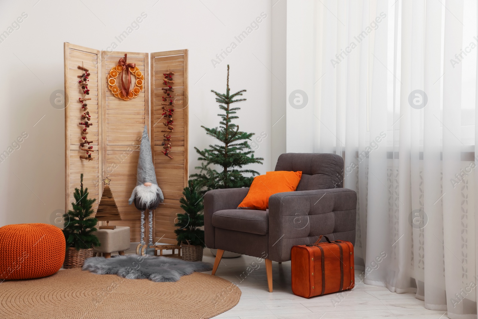 Photo of Beautiful Christmas themed photo zone with trees, dwarf and armchair in room