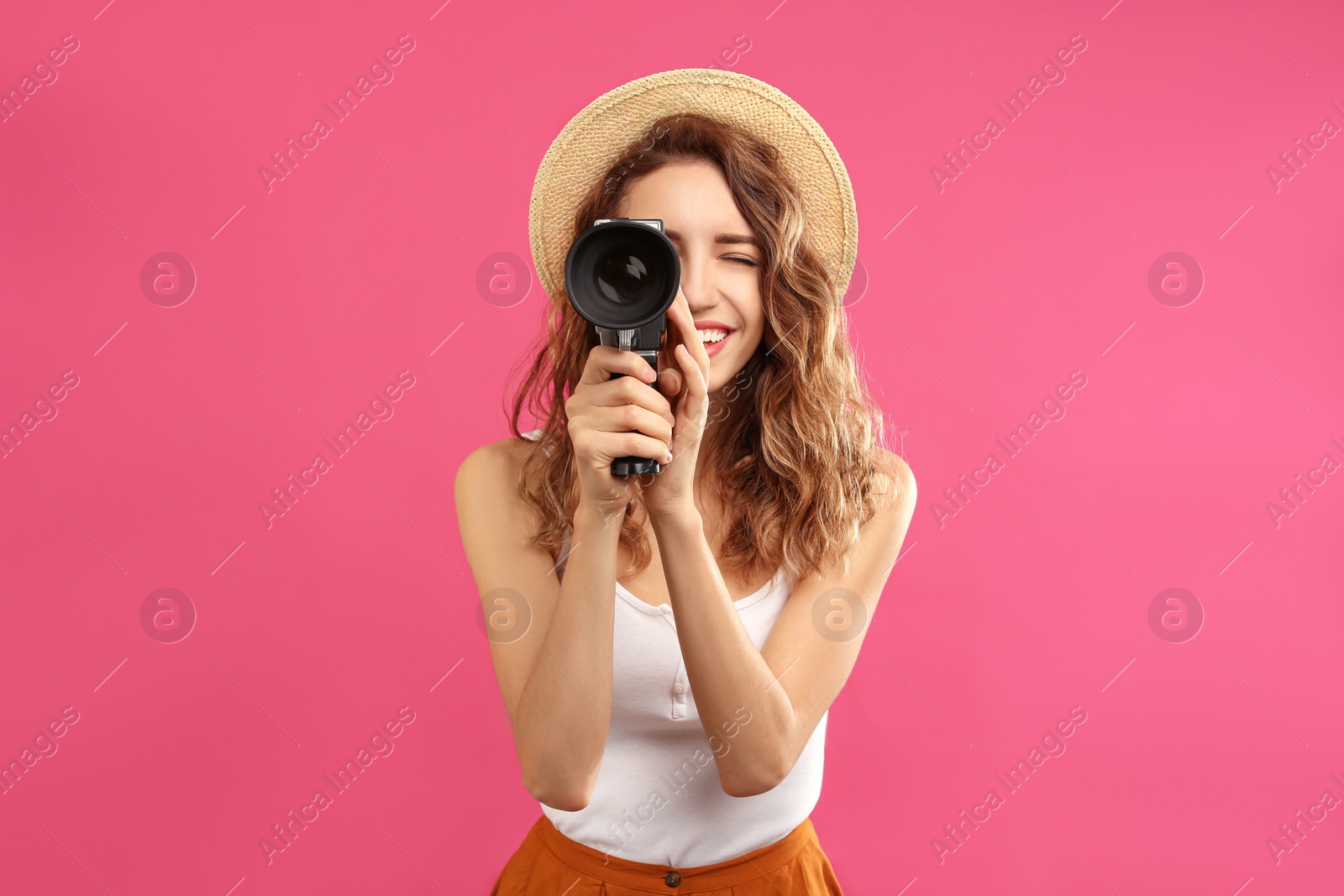 Photo of Beautiful young woman using vintage video camera on crimson background