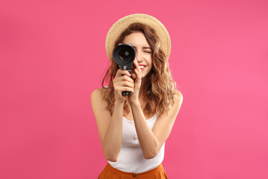 Beautiful young woman using vintage video camera on crimson background