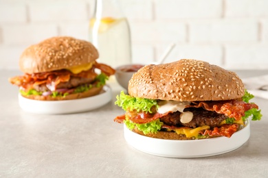 Photo of Tasty burgers with bacon on table