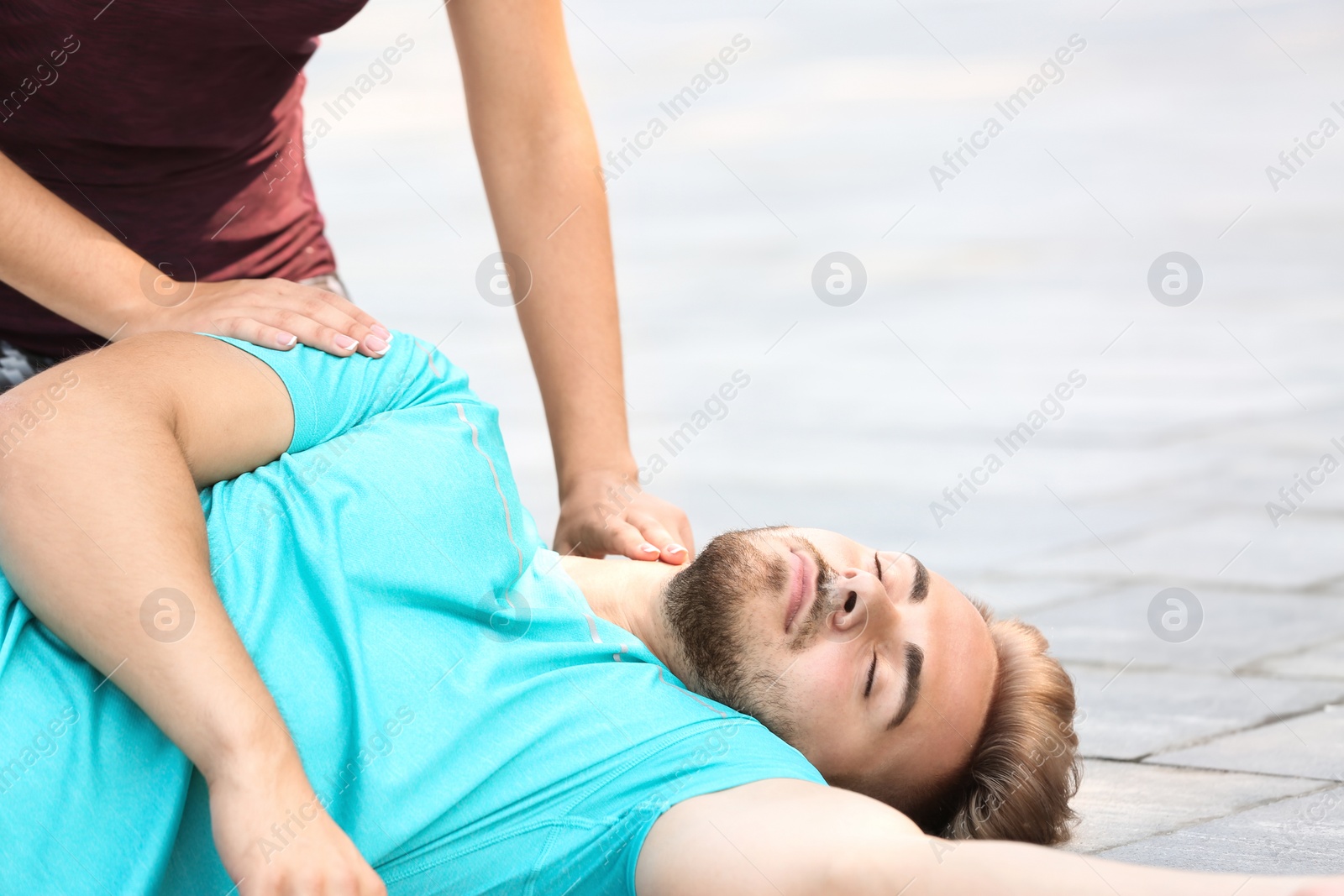 Photo of Woman checking pulse of unconscious man outdoors