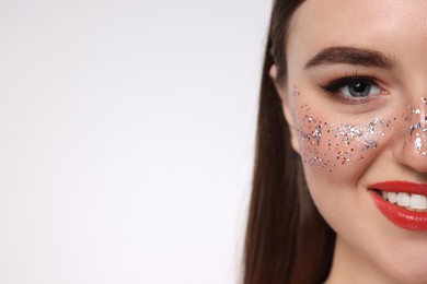 Photo of Happy woman with glitter freckles on light background, closeup. Space for text