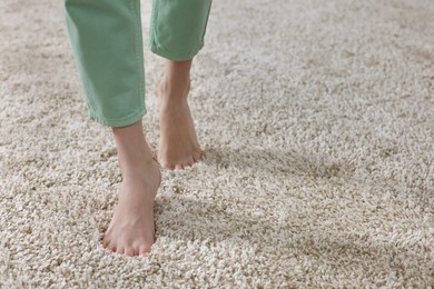 Photo of Woman walking on soft beige carpet at home, closeup. Space for text