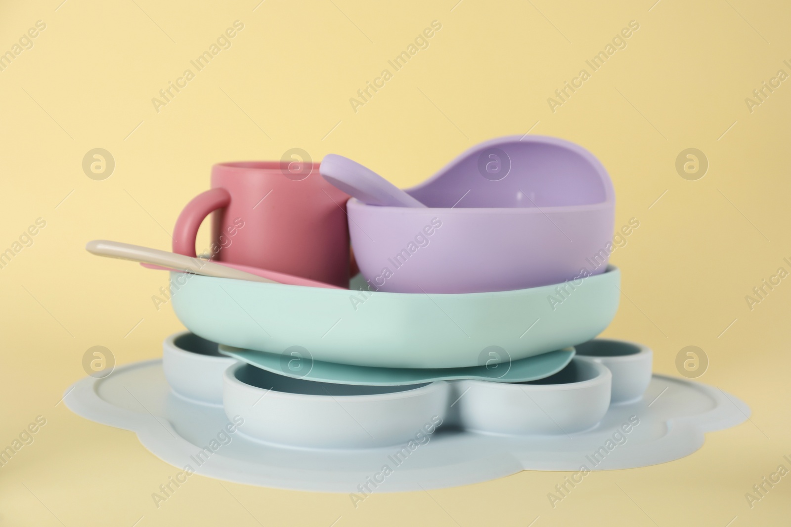 Photo of Set of plastic dishware on beige background. Serving baby food