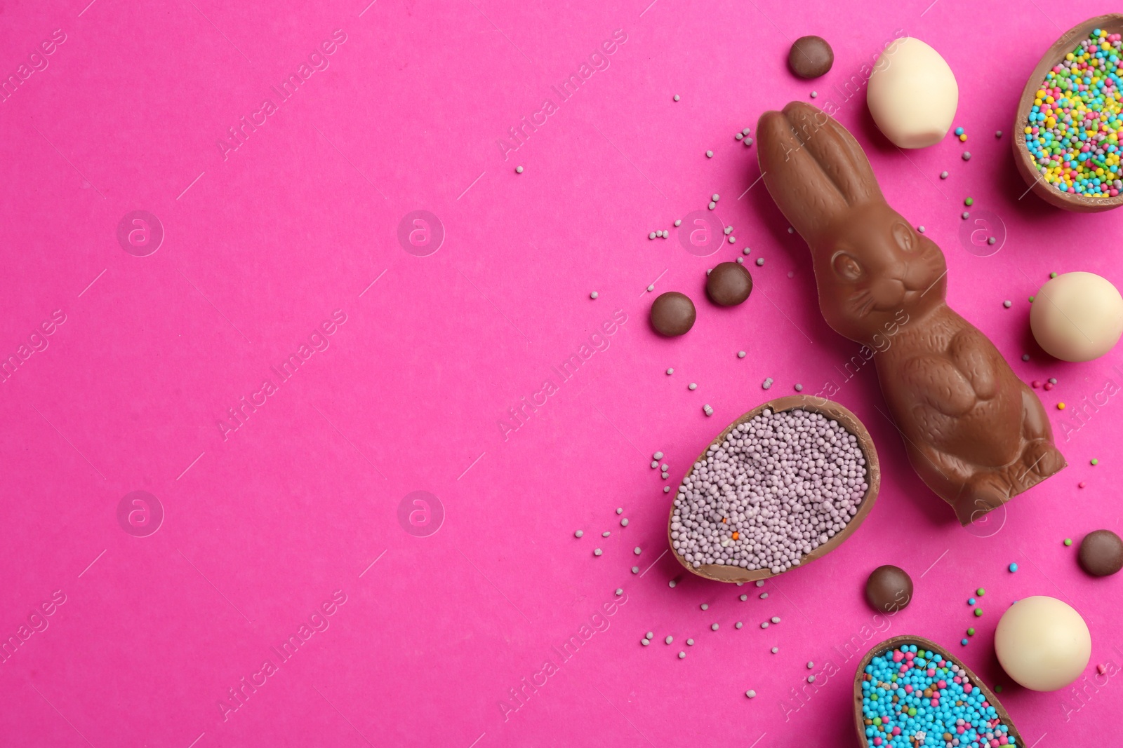 Photo of Flat lay composition with chocolate Easter bunny, candies and eggs on pink background. Space for text