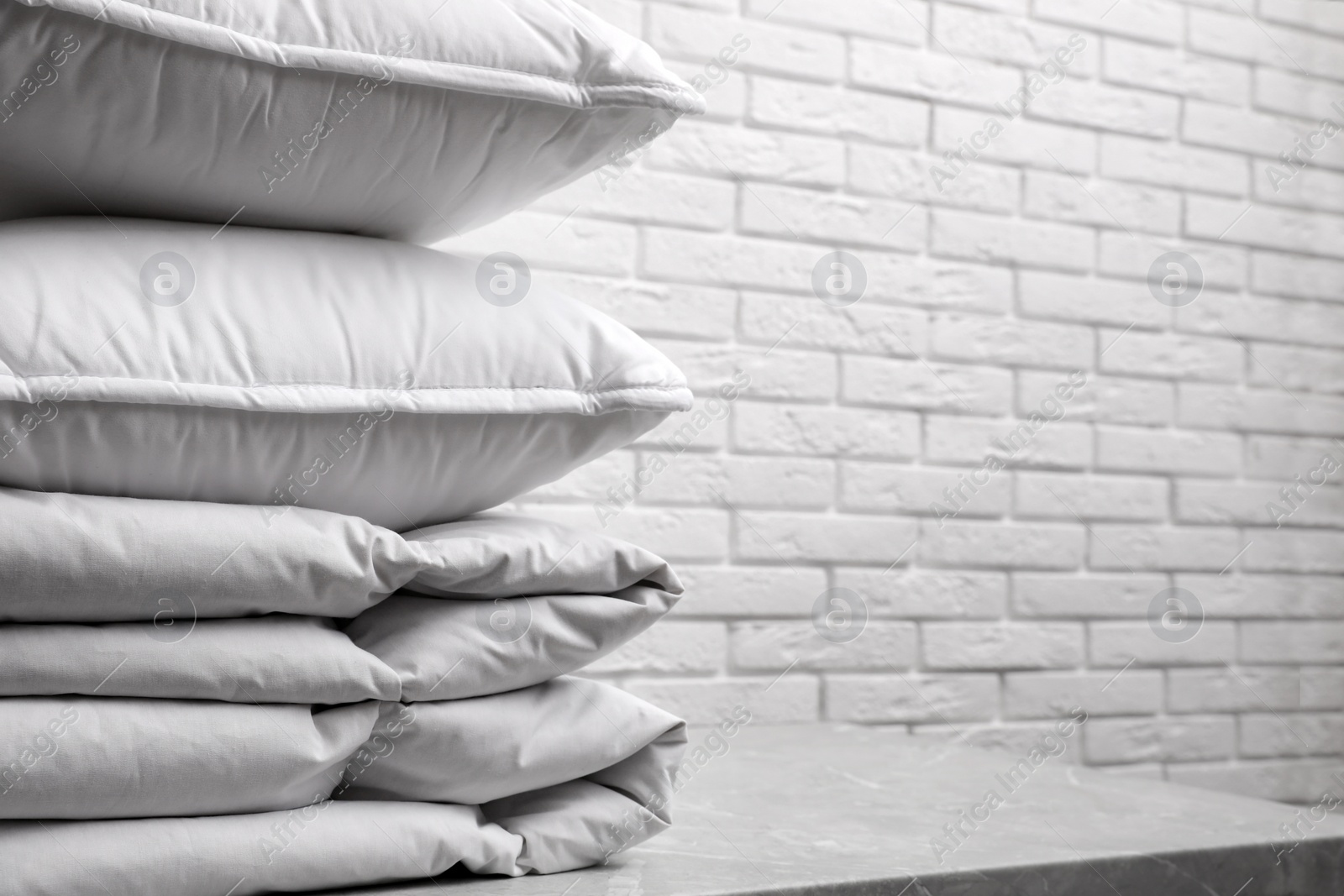 Photo of Soft folded blanket and pillows on table, closeup. Space for text