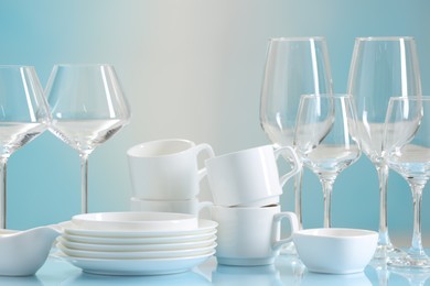 Photo of Set of many clean dishware and glasses on light blue table