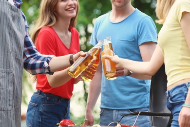 Photo of Young people with bottles of beer outdoors. Summer picnic