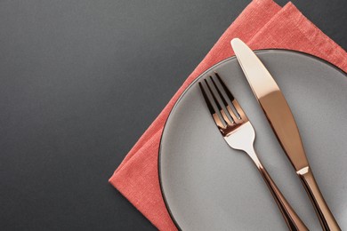 Clean plate, cutlery and napkin on grey table, top view. Space for text