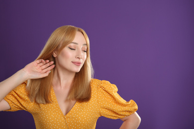 Beautiful young woman with blonde hair on purple background. Space for text