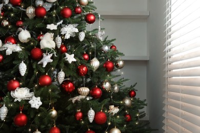 Photo of Beautifully decorated Christmas tree near window indoors