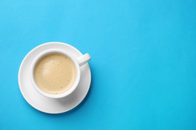 Photo of Aromatic coffee in cup on light blue background, top view. Space for text