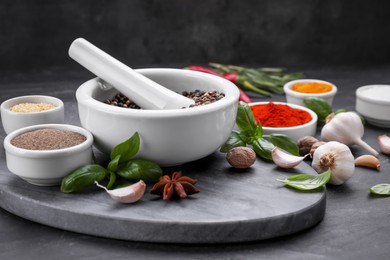 Photo of Mortar with pestle and different spices on black table, space for text