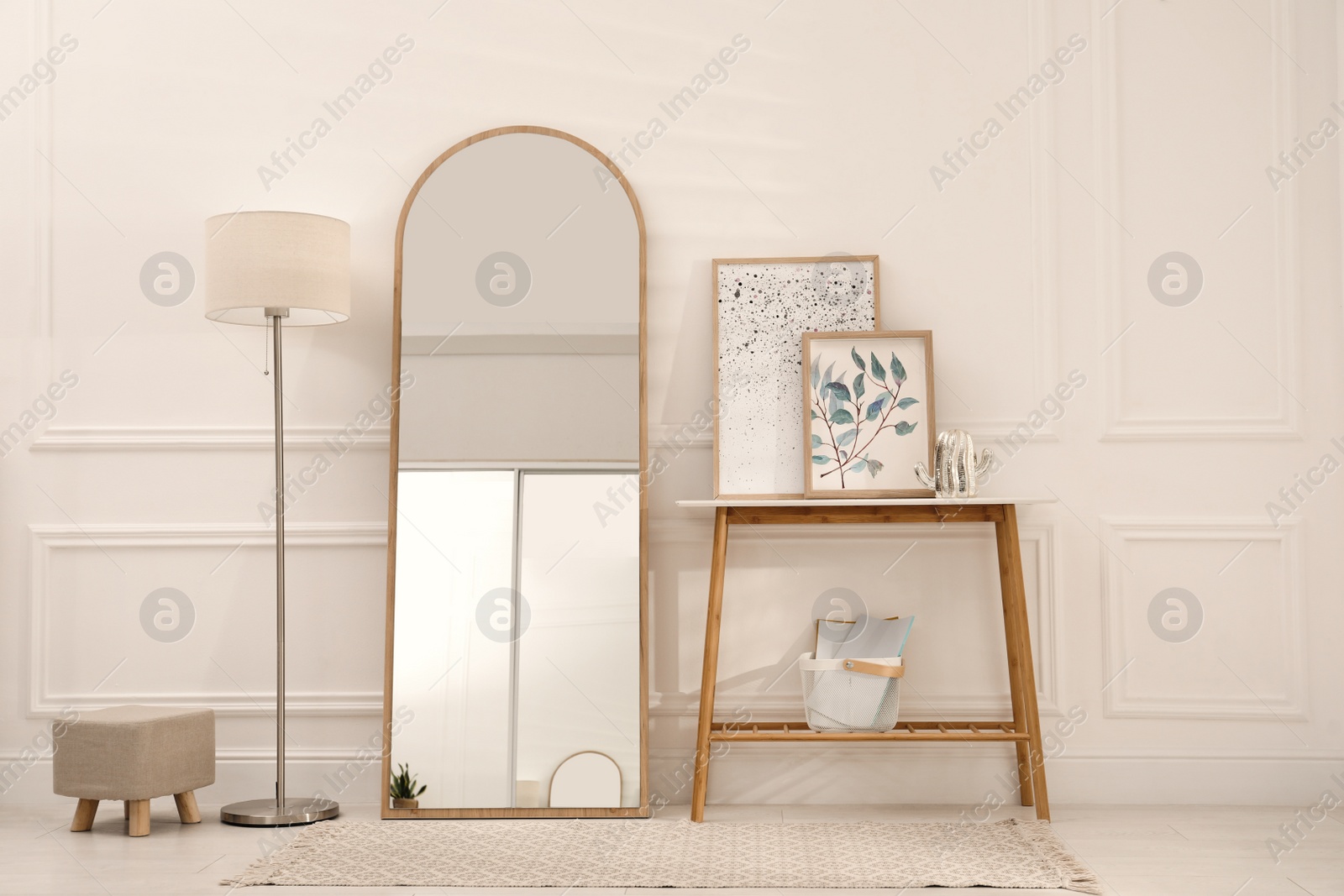 Photo of Beautiful mirror, console table and lamp near white wall indoors. Interior design