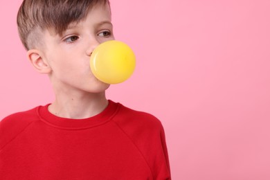 Photo of Boy blowing bubble gum on pink background, space for text