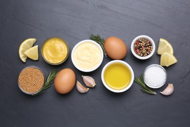 Photo of Delicious homemade mayonnaise, spices and ingredients on black table, flat lay