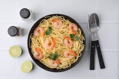 Photo of Tasty spaghetti with shrimps and parsley in bowl served on light tiled table, flat lay