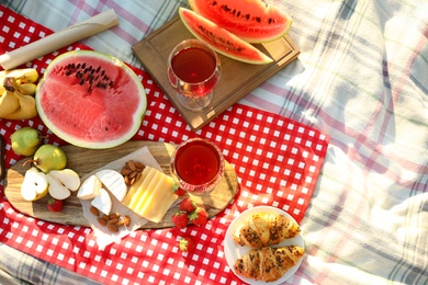 Photo of Picnic blanket with delicious food and drinks outdoors on sunny day, flat lay