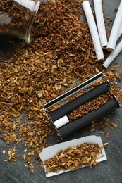 Photo of Flat lay composition with roller and tobacco on dark grey table. Making hand rolled cigarettes