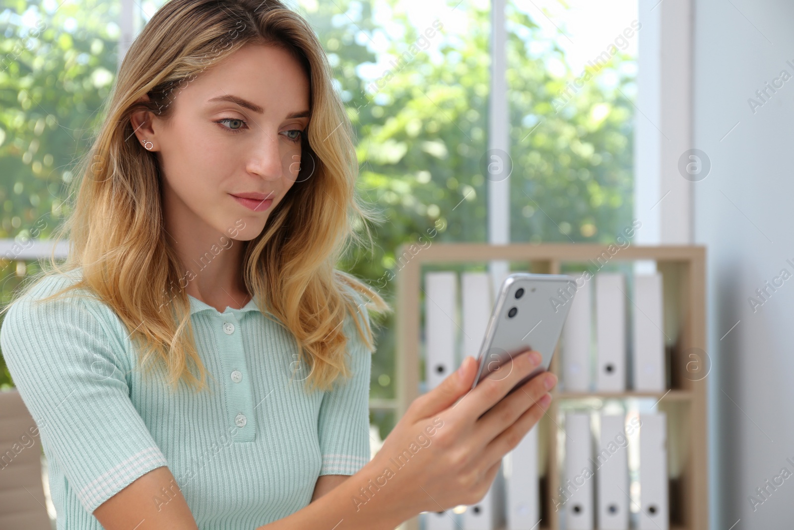 Photo of Young woman unlocking smartphone with facial scanner indoors. Biometric verification