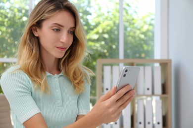 Young woman unlocking smartphone with facial scanner indoors. Biometric verification