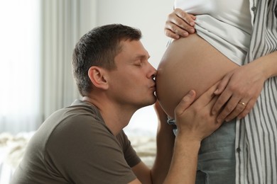 Photo of Young pregnant woman with her husband at home, closeup