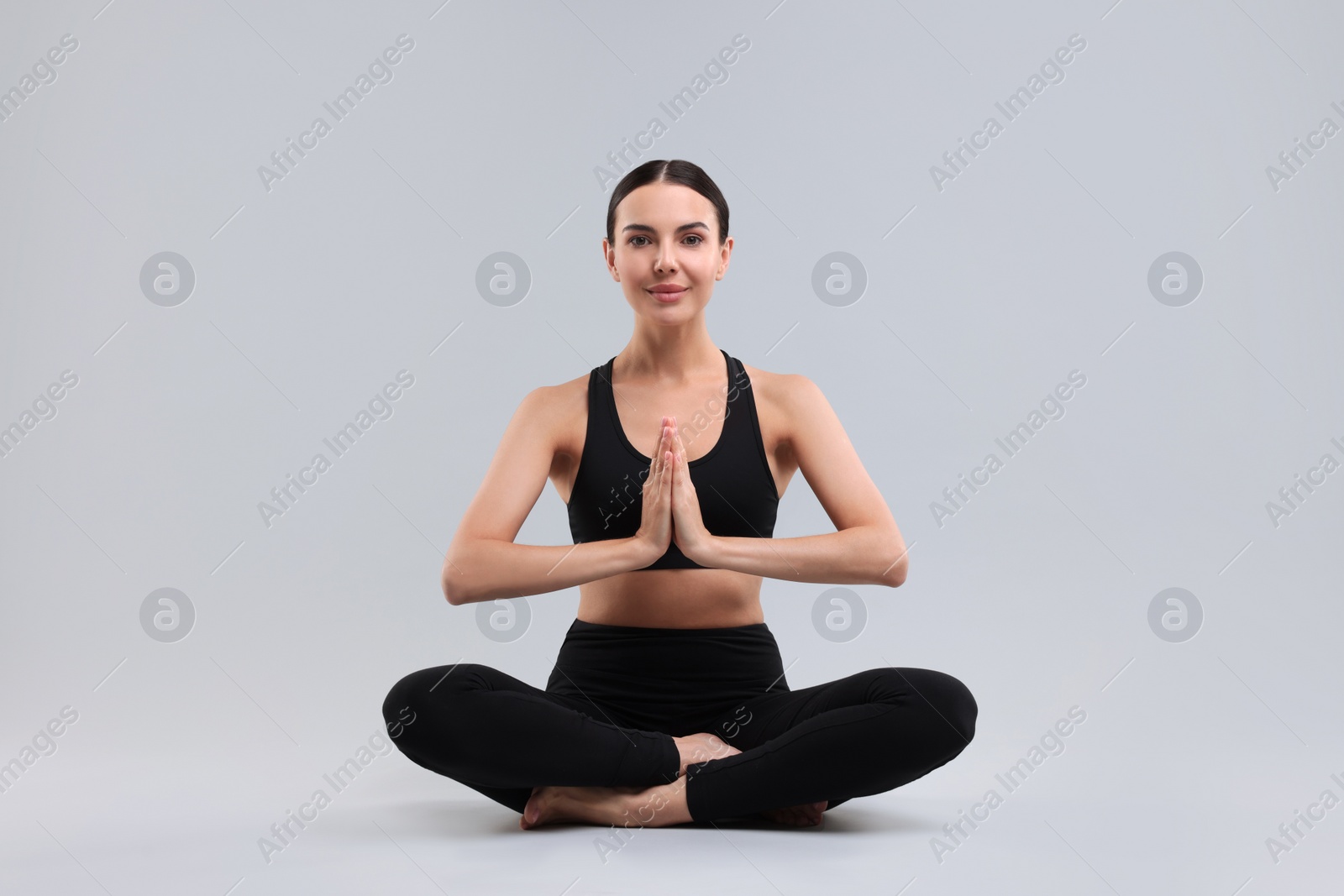 Photo of Beautiful young woman practicing yoga on grey background. Lotus pose