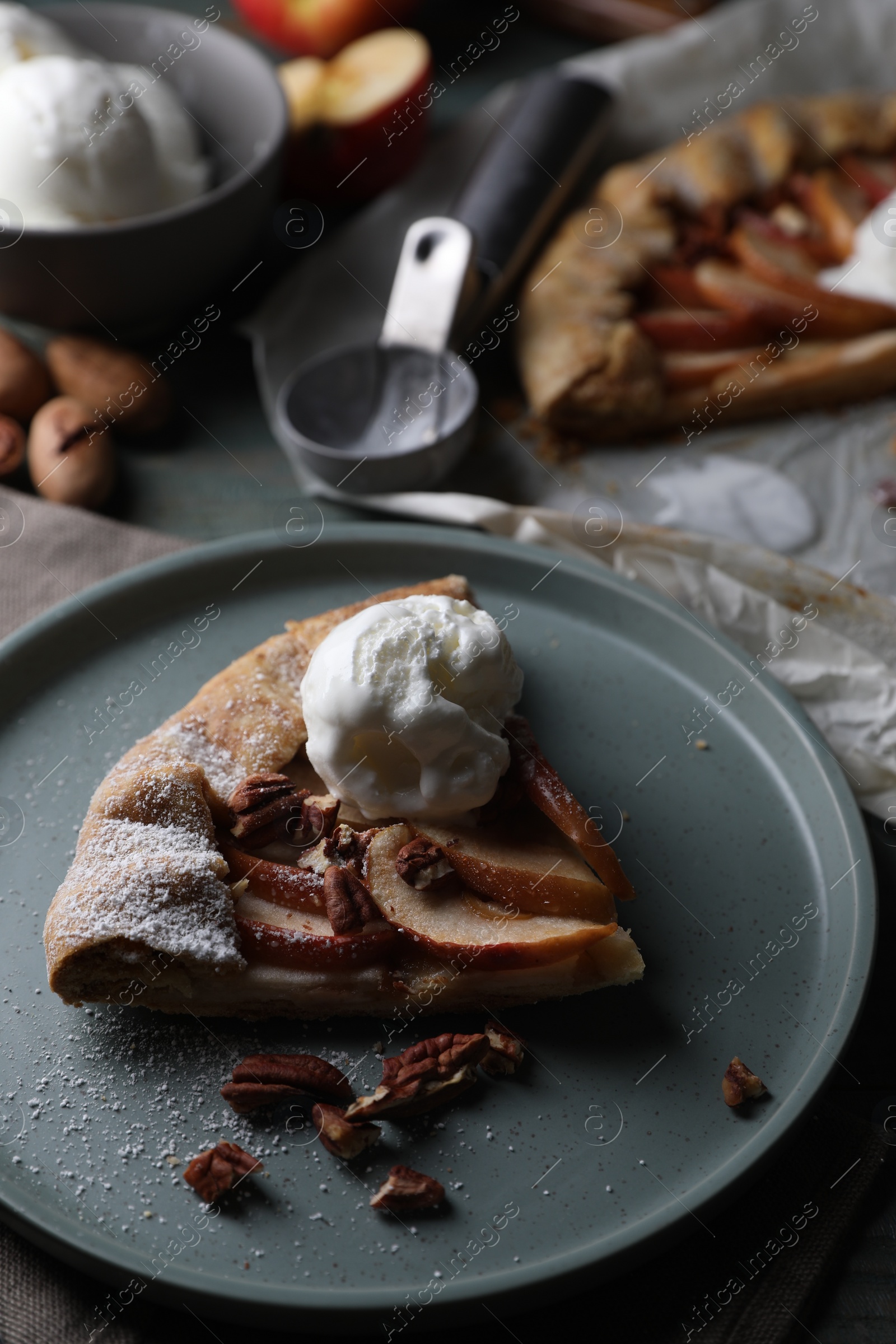 Photo of Delicious apple galette with ice cream and pecans on wooden table